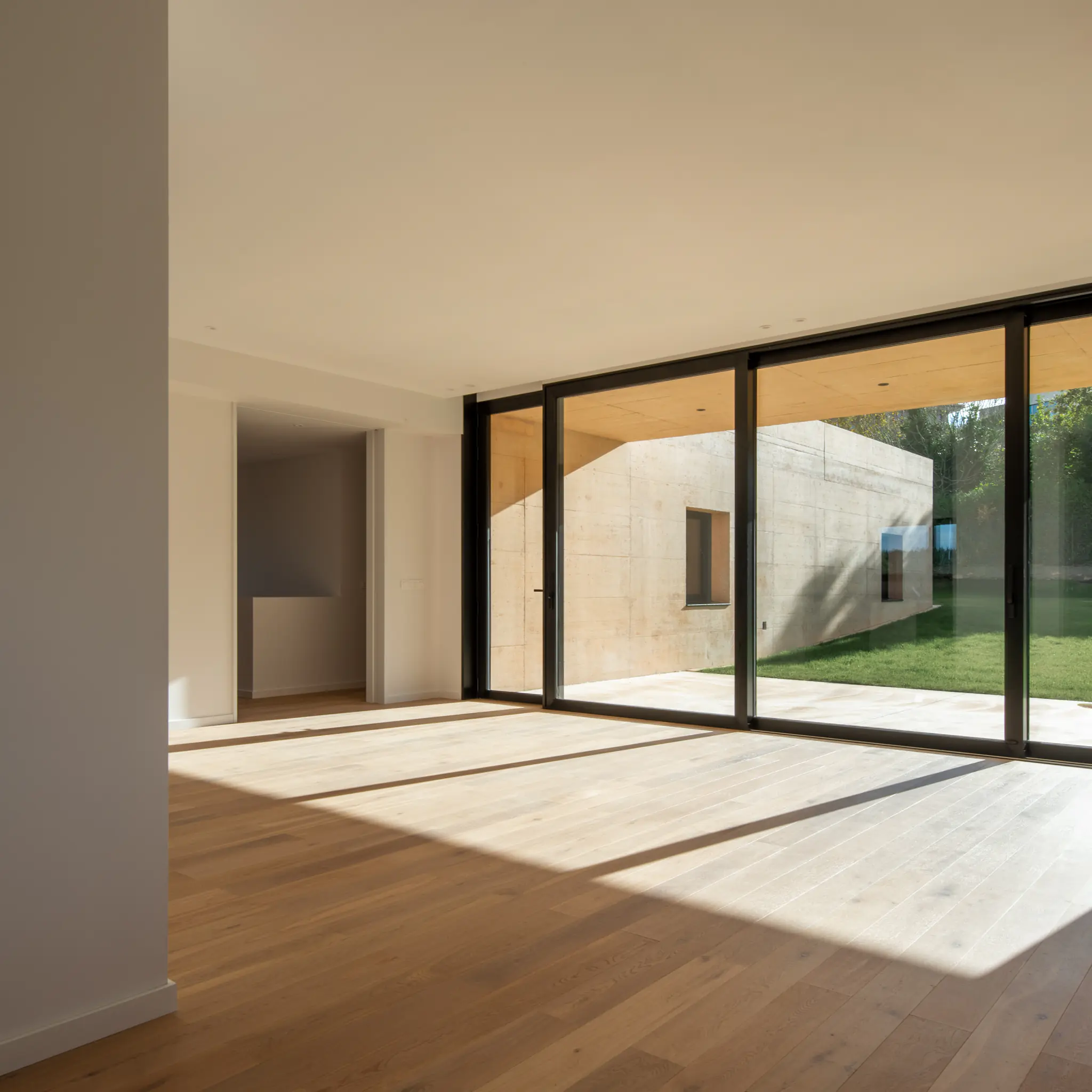 Salón de vivienda unifamiliar moderna abierto al patio mediante grandes ventanales, diseñado por SEA arquitectos.