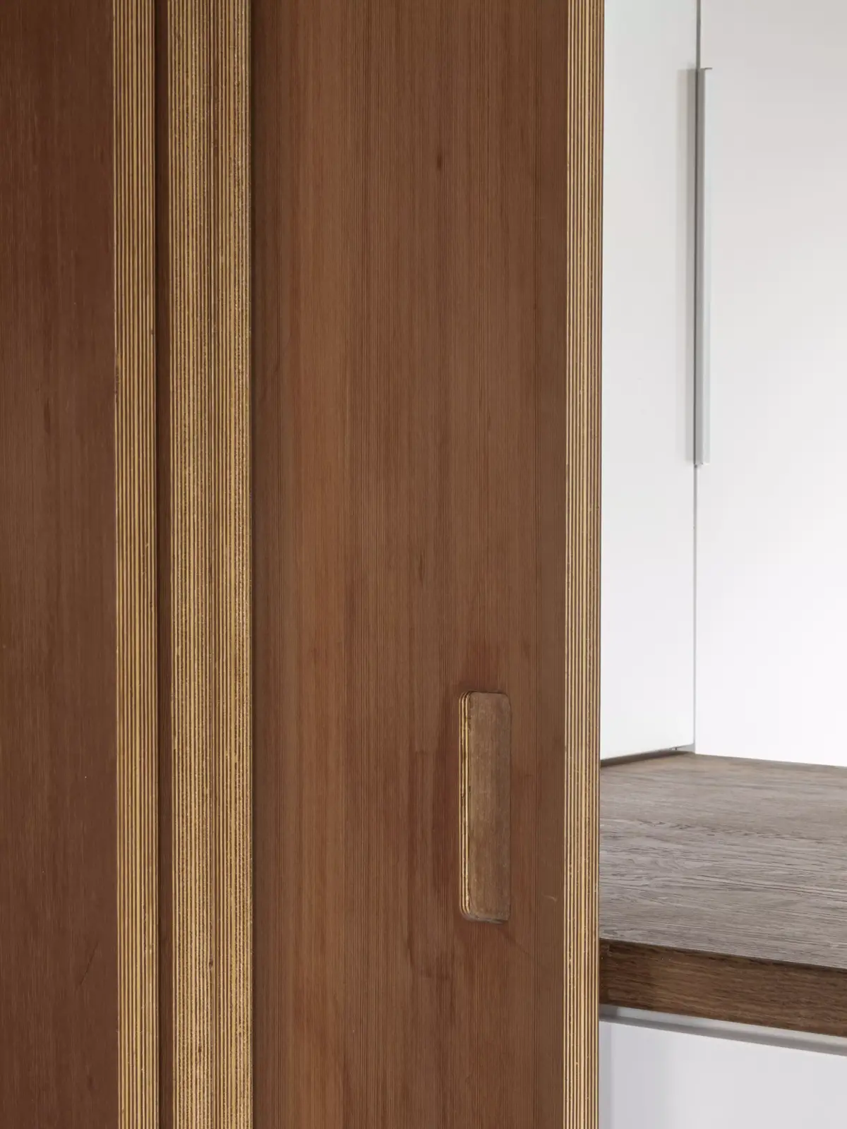 Detalle de puerta corredera en madera de cedro con tirador integrado, diseñado en Narón por estudio de arquitectura SEA.
