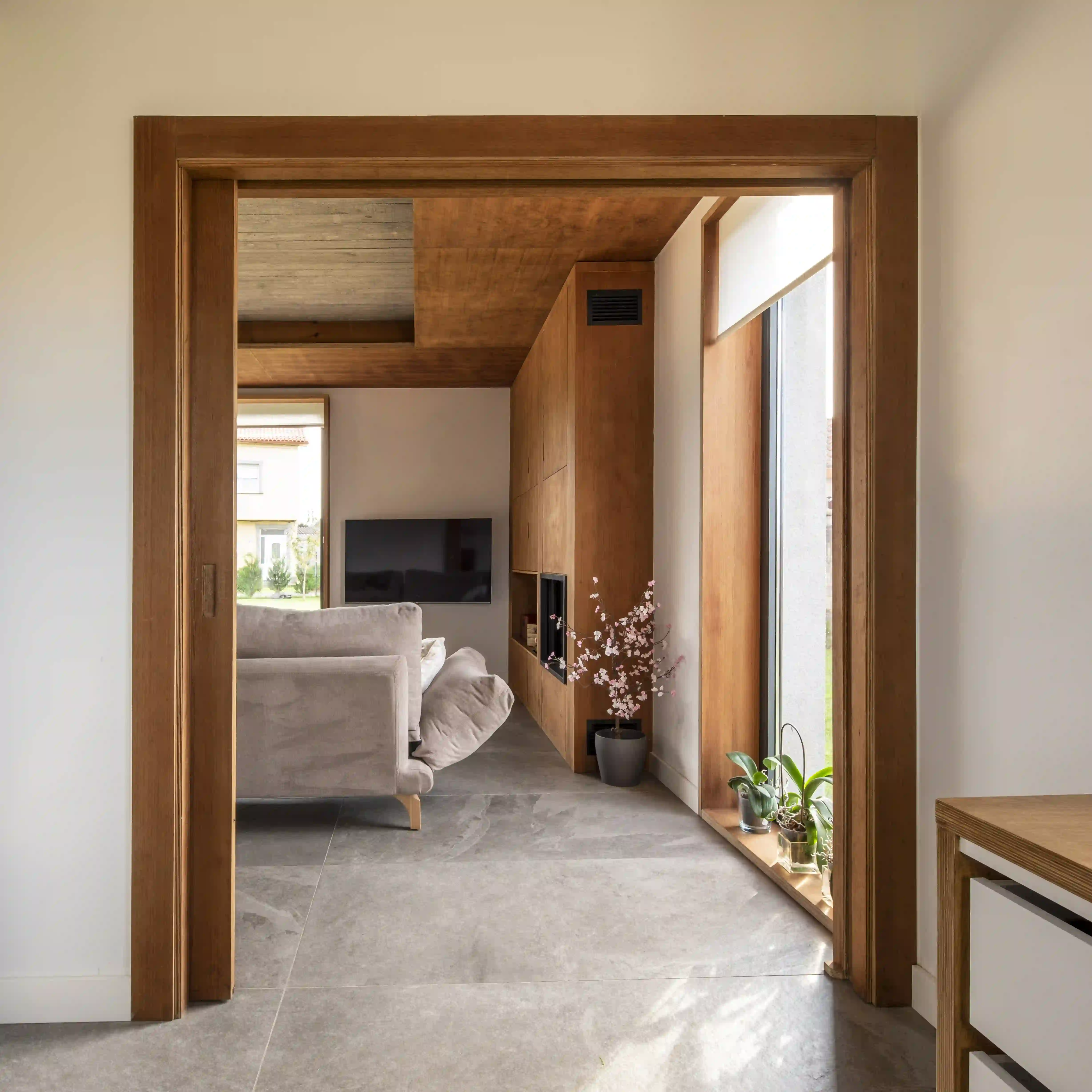 Interior de vivienda en Narón con puertas correderas de madera de cedro y espacios versátiles diseñada por estudio de arquitectura SEA.