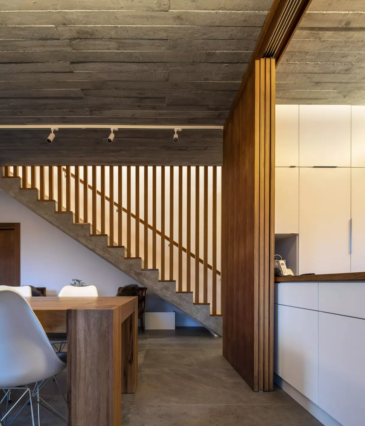 Interior de vivienda en Narón con contraste de hormigón visto, madera de cedro en escalera y paneles correderos diseñados por SEA Arquitectos.