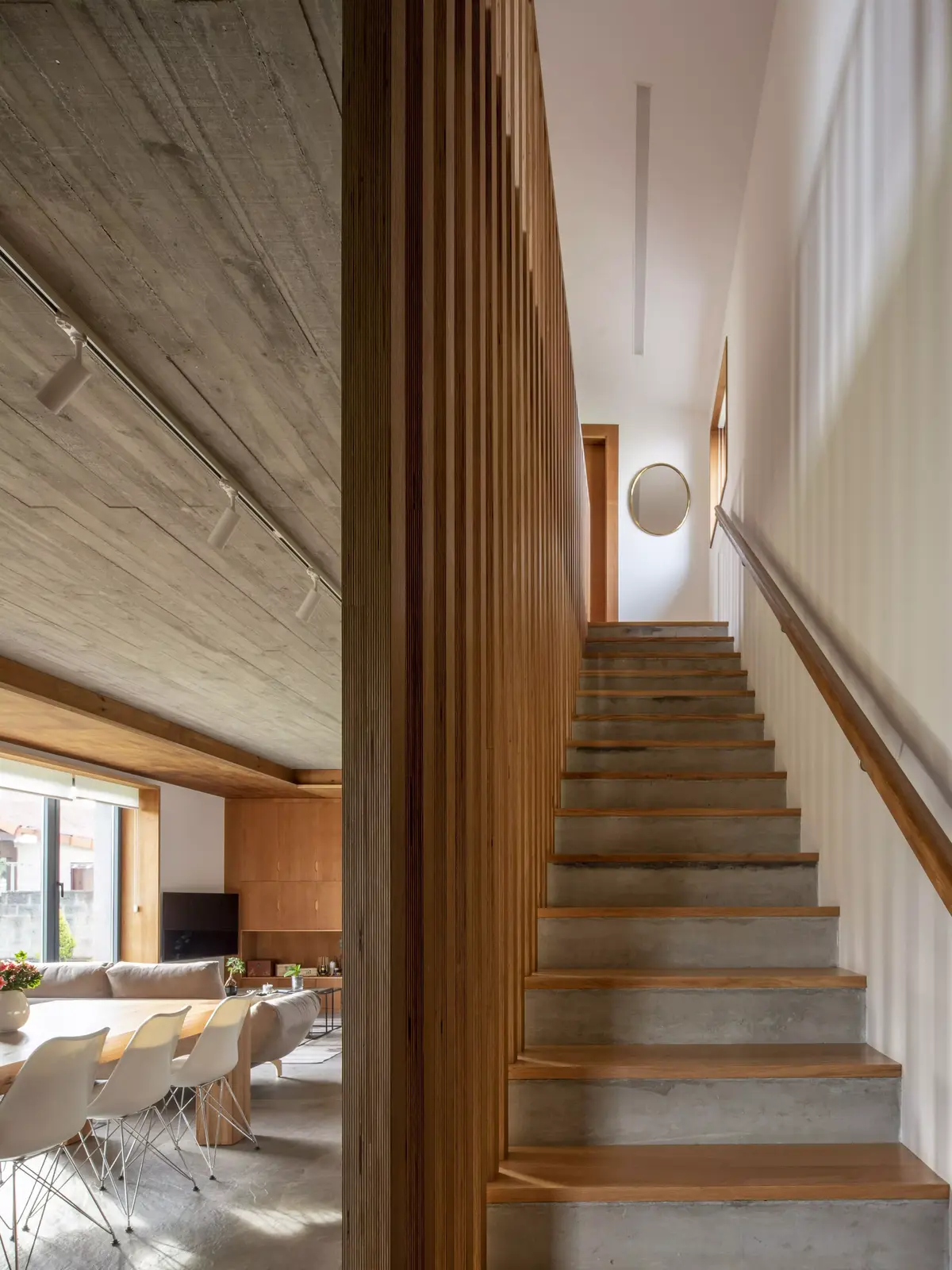 Vivienda unifamiliar en Narón con salón comedor, techo de hormigón visto y una escalera de hormigón y madera con un pasamanos ergonómico diseñado por SEA Arquitectos.